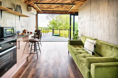 a living room with a green couch and a kitchen at Rusty Boathouse in Llanarth