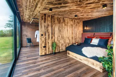 a bedroom with a bed and a wooden wall at Rusty Boathouse in Llanarth