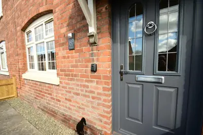 a black cat sitting next to a brick building with a door at Old Street Terrace in Ludlow