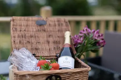 a basket with a bottle of wine and strawberries at Blaenplwyf Shire Pods in Lampeter