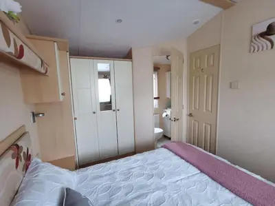 a bedroom with a large bed and a bathroom at Sea and Mountain view Sunbeach Holiday Snowdonia in Llwyngwril