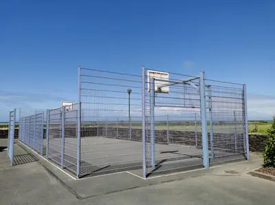 a large metal fence with a basketball court at Sea and Mountain view Sunbeach Holiday Snowdonia in Llwyngwril