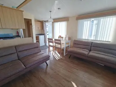 a living room with two brown couches and a table at Sea and Mountain view Sunbeach Holiday Snowdonia in Llwyngwril
