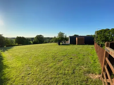 a field of grass with a fence and a building at Cherry Pod in Shrewsbury