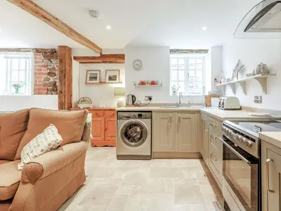 a kitchen with a couch and a washer and dryer at The Old Milking Parlour in Wentnor