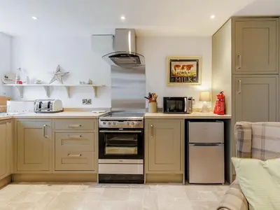 a kitchen with a stove top oven next to a couch at The Old Milking Parlour in Wentnor