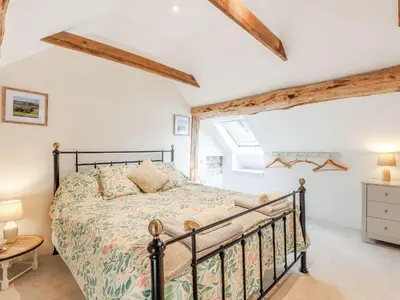 a bedroom with a bed in a room with wooden beams at The Old Milking Parlour in Wentnor
