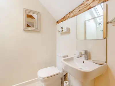 a white bathroom with a sink and a toilet at The Old Milking Parlour in Wentnor