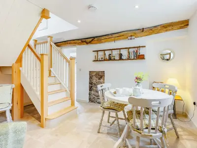 a dining room with a table and chairs and a staircase at The Old Milking Parlour in Wentnor