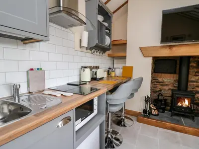 a kitchen with a stove top oven next to a fireplace at The Old Cobblers Shop in Llandrindod Wells