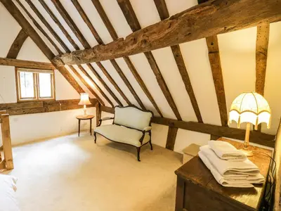a attic room with a chair and a table at Manor Cottage in Church Stretton