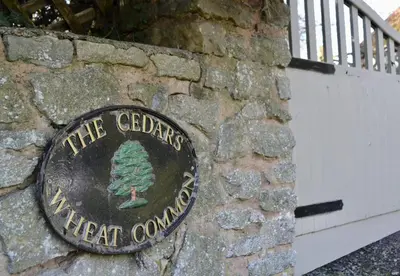a sign on a stone wall with a tree on it at The Cedars Ludlow in Lane to Richards Castle