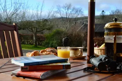 a table with books and a glass of orange juice and bread at The Cedars Ludlow in Lane to Richards Castle