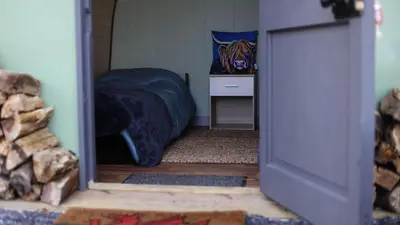 a bedroom with a bed and a table in a room at MotoCamp Wales -Camping Pods in Dolgellau