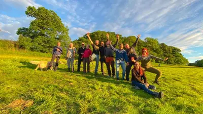 a group of people standing in a field with their hands in the air at MotoCamp Wales -Camping Pods in Dolgellau