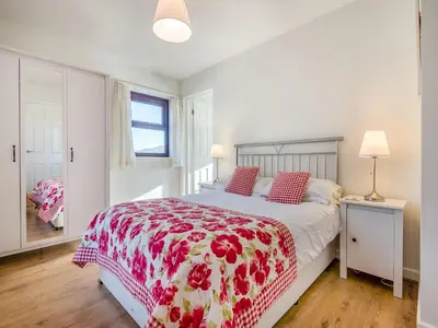 a bedroom with a bed with a red and white comforter at Beacons Cottage-Uk36406 in Bronllys