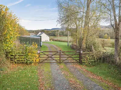 a gate in a field with a dirt road at Beacons Cottage-Uk36406 in Bronllys