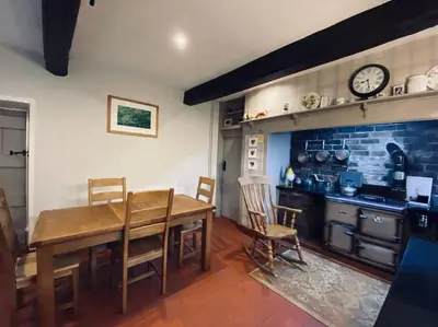 a kitchen with a wooden table and a clock on the wall at Farmhouse Cottage set in beautiful countryside in Oswestry