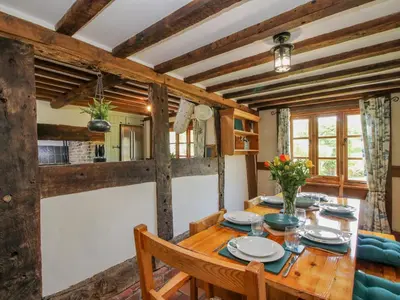 a dining room with a wooden table and chairs at 46-47 Lydbury North in North Lydbury