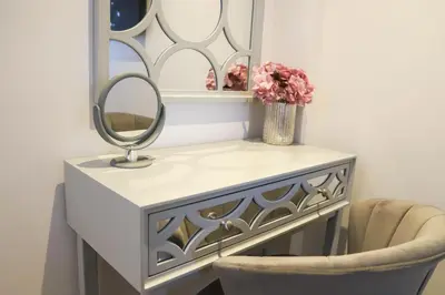 a dressing table with a mirror and a vase of flowers at Apartment Seven in Shrewsbury