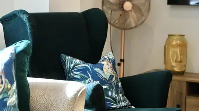 a living room with a blue chair with pillows at Apartment Seven in Shrewsbury