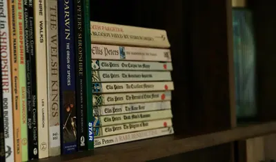 a stack of books sitting on a shelf at Apartment Seven in Shrewsbury