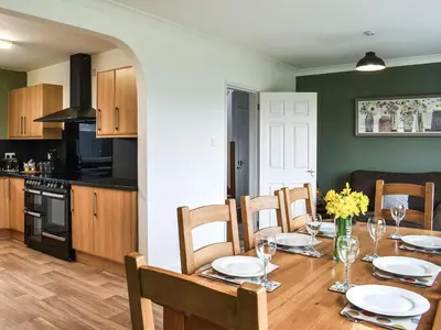 a kitchen with a table with chairs and a dining room at Llwyn in Bettws Gwerfil Goch