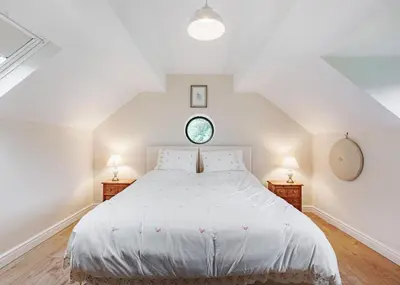 a bedroom with a large white bed and two lamps at Sgubor Fach in Pen-y-bont-fawr