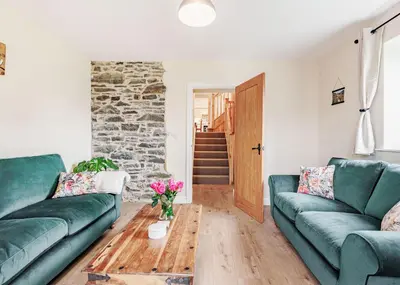 a living room with two green couches and a table at Sgubor Fach in Pen-y-bont-fawr