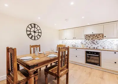 a kitchen with a wooden table and a clock on the wall at Sgubor Fach in Pen-y-bont-fawr