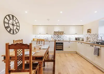 a kitchen with a table and a clock on the wall at Sgubor Fach in Pen-y-bont-fawr