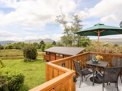 a deck with a table and an umbrella at Ty Coed - 63 in Trawsfynydd