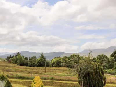 a field with trees and mountains in the distance at Ty Coed - 63 in Trawsfynydd