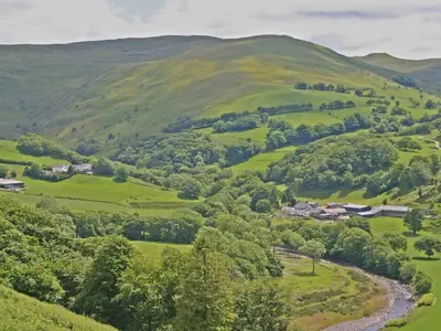 a valley of green hills with houses and a river at Penroc in Pentre-briwnant