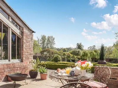 a patio with a table and chairs and flowers at The Bothy - Uk33692 in Bicton