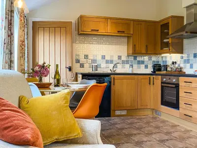 a kitchen with wooden cabinets and a yellow pillow at The Bothy - Uk33692 in Bicton