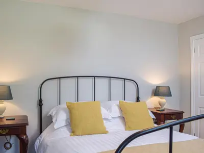 a bedroom with a bed with yellow pillows and two tables at The Bothy - Uk33692 in Bicton