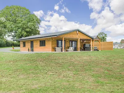 a log cabin with a large grass field at Oak Tree Lodge - Uk38383 in Lyonshall