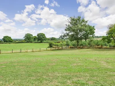 a large field with a fence and a tree at Oak Tree Lodge - Uk38383 in Lyonshall