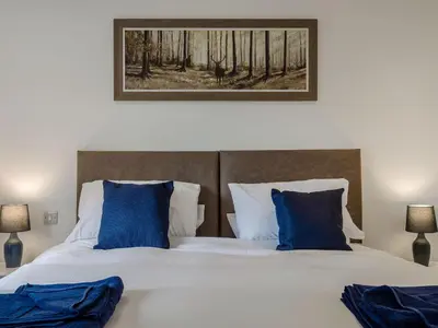 a bedroom with a large bed with blue pillows at Bramley Lodge - Uk38384 in Lyonshall