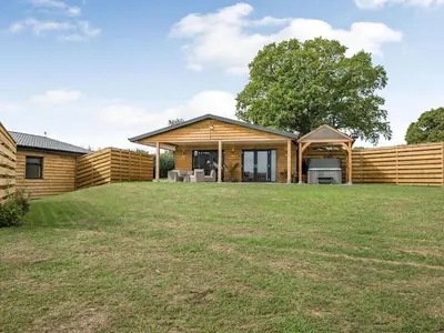 a timber house with a lawn in front of it at Bramley Lodge - Uk38384 in Lyonshall