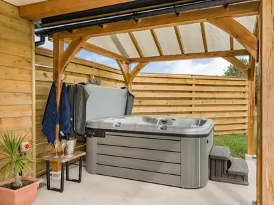 a hot tub on a patio under a pergola at Bramley Lodge - Uk38384 in Lyonshall