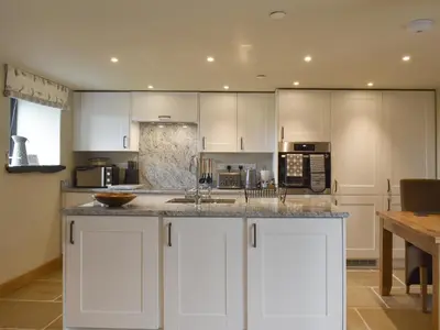a kitchen with white cabinets and a counter top at The Shippon in Gwyddelwern