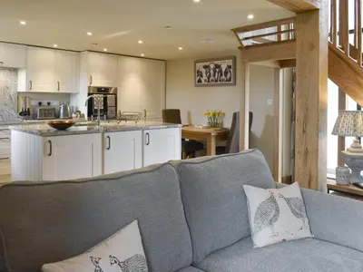 a living room with a couch and a kitchen at The Shippon in Gwyddelwern