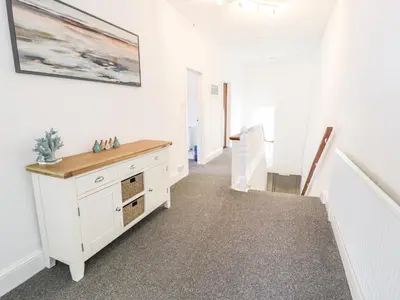 a hallway with white walls and a white dresser at 4A Victoria Place in Barmouth