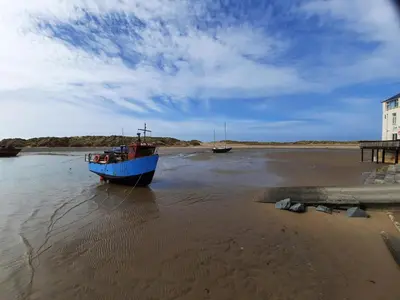 a blue boat sitting in the water on the beach at 4A Victoria Place in Barmouth