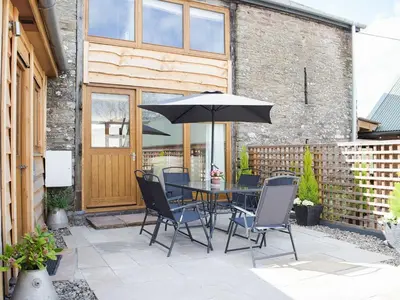 a patio with a table and chairs and an umbrella at Horsecroft - Uk37462 in Dorstone