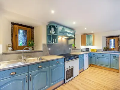 a large kitchen with blue cabinets and a sink at Horsecroft - Uk37462 in Dorstone