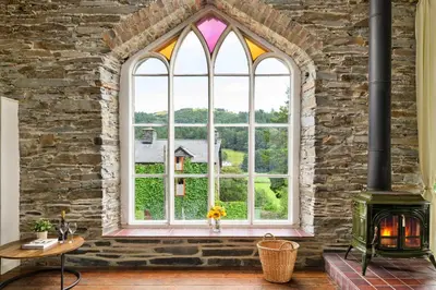 a room with a large window and a fireplace at Finest Retreats - Luxury Converted Chapel with Hot Tub & Games Room in Dinas Mawddwy