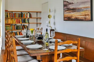 a dining room table with chairs and wine glasses at Finest Retreats - Luxury Converted Chapel with Hot Tub & Games Room in Dinas Mawddwy